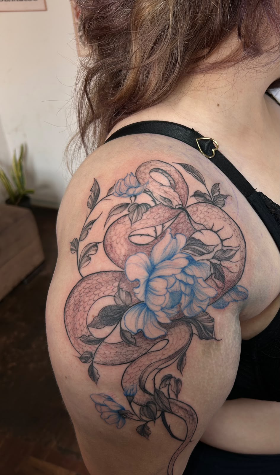 Tatuagem autoral de serpente e flores no braço