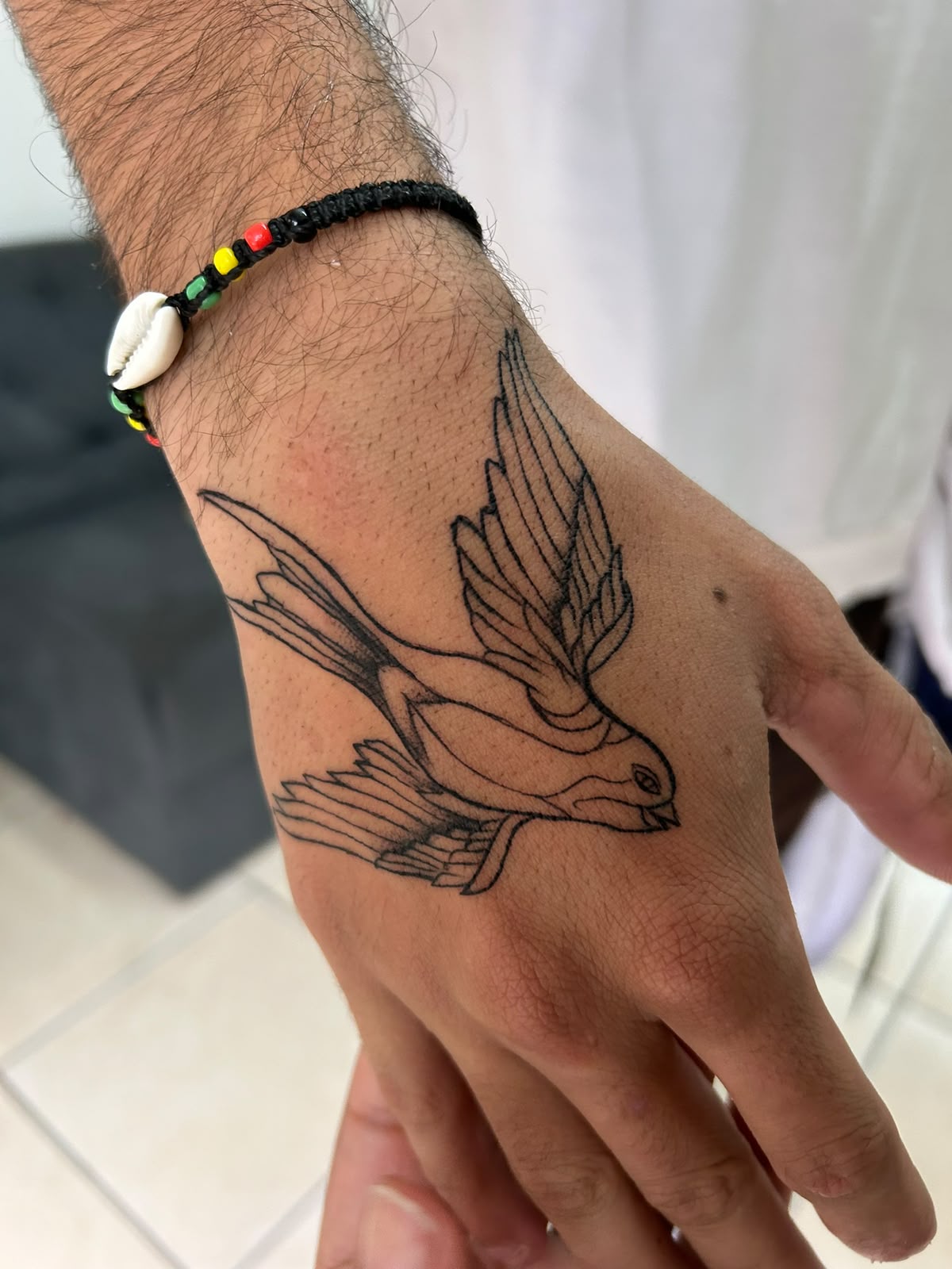 Tatuagem fine line de andorinha na mão